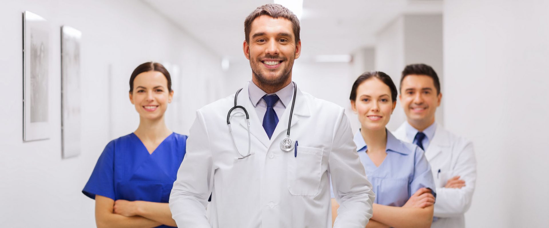 clinic, profession, people, health care and medicine concept - happy group of medics or doctors at hospital corridor